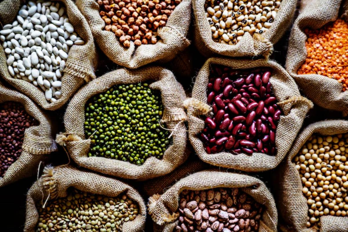 Aerial view of burlap sacks filled with various colorful beans and lentils, showcasing diverse textures and colors.